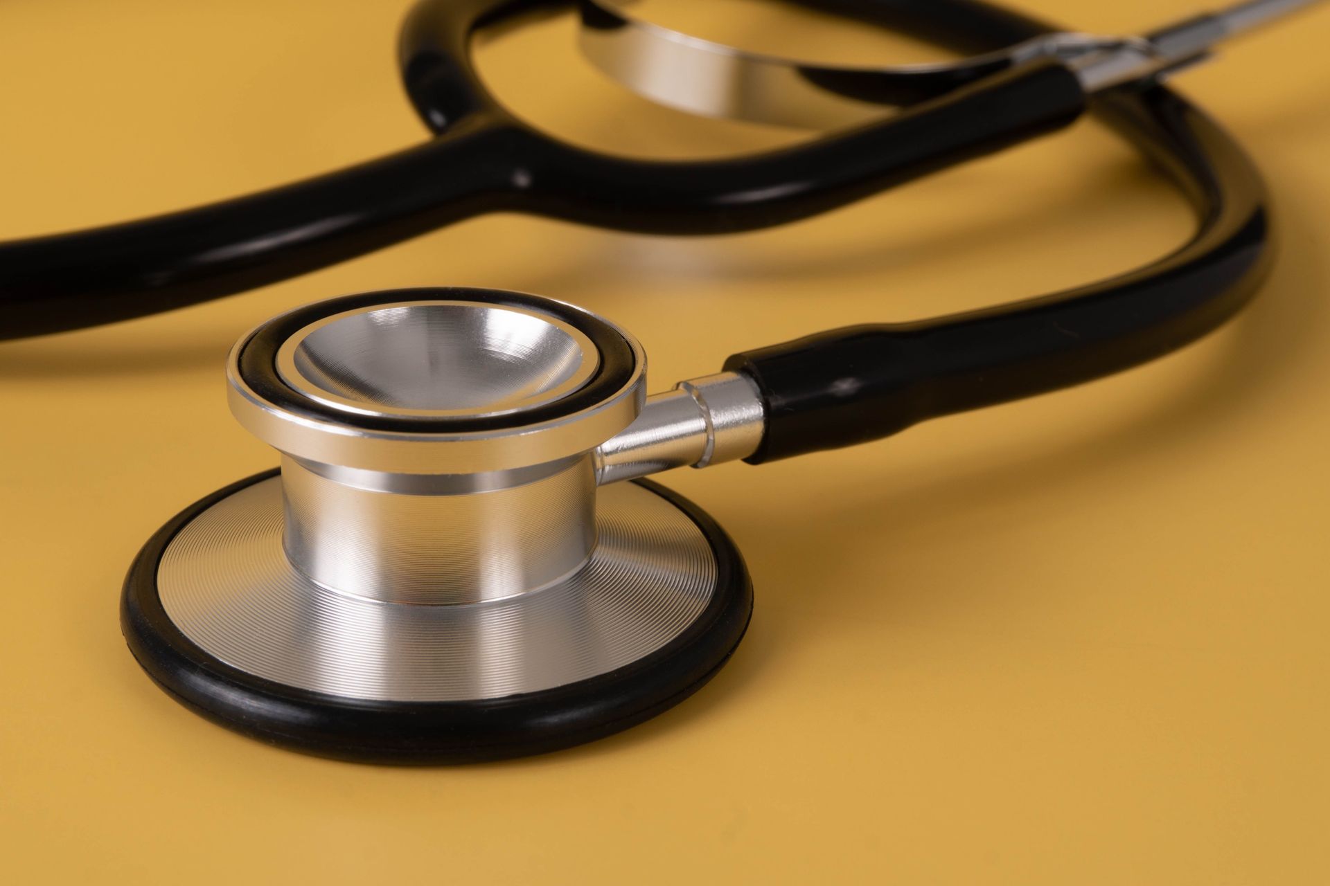 Detailed image of a stethoscope on a vibrant yellow surface.